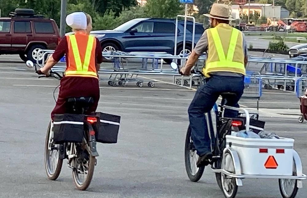 Amish couple riding e-bikes with safety vests on a Holmes County road